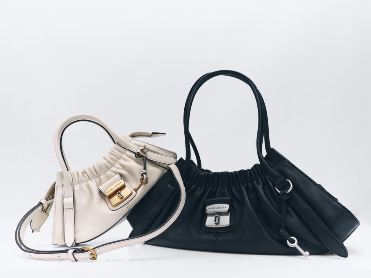 Two leather handbags, one off-white and one black, displayed on a clean white seamless studio background.