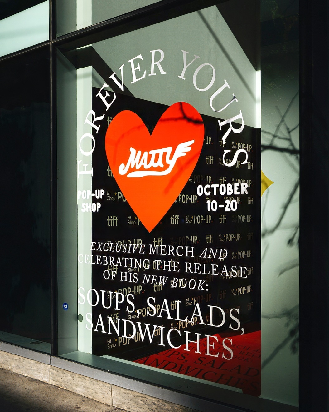 Storefront window display with white typography and a large red heart graphic promoting a Matty Matheson pop-up shop event