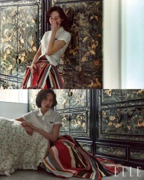 Model Song Ah Woo in a white short-sleeve top and multi-colored striped skirt against an ornate dark cabinet for Elle Korea.