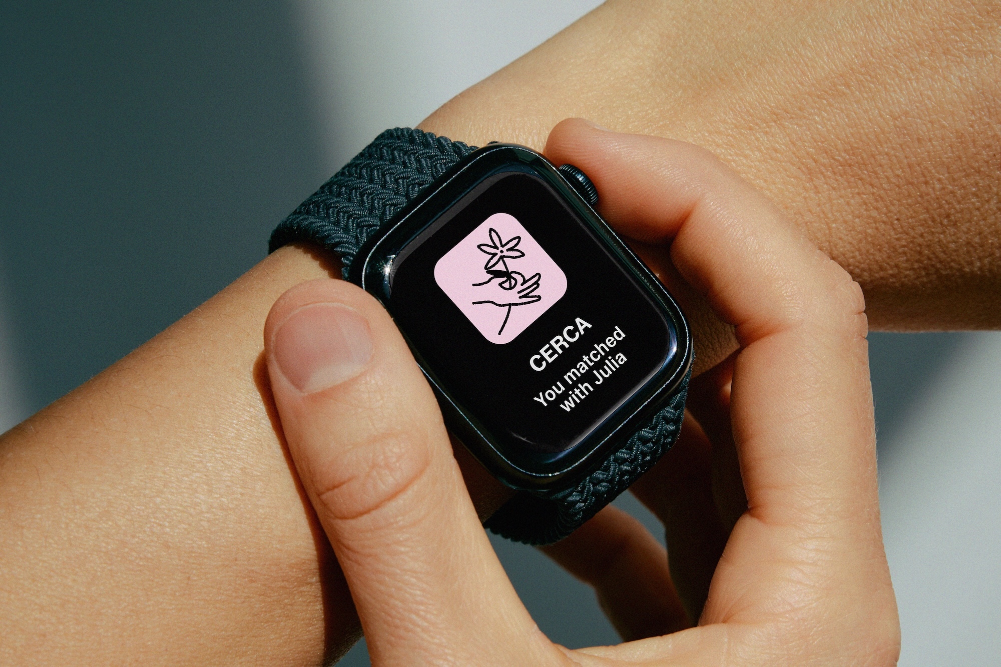 Close-up of a smartwatch with a dark woven band displaying the CERCA brand interface on a person's wrist.