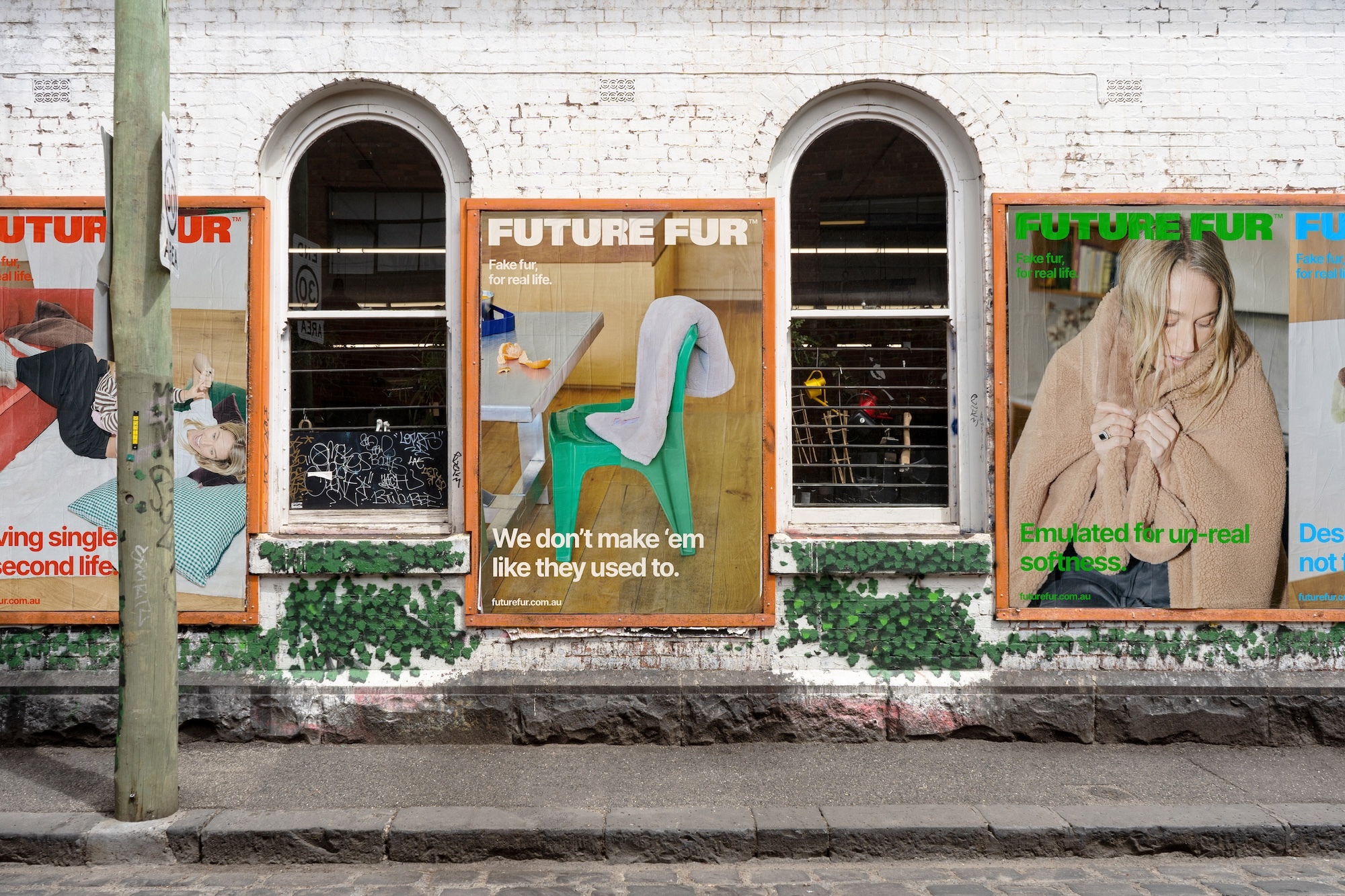 Outdoor posters for Future Fur brand identity pasted on a white brick wall with arched windows and painted ivy
