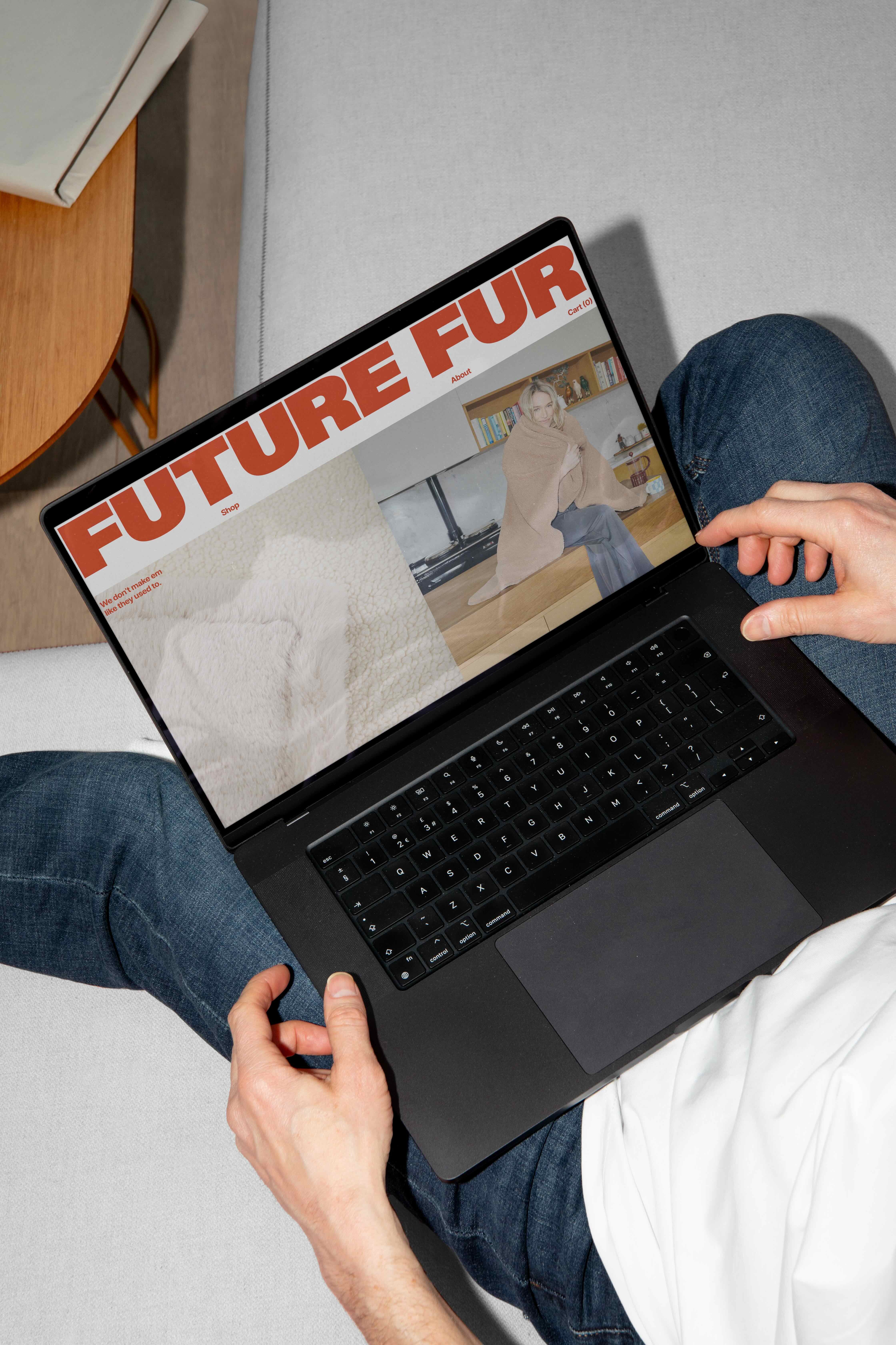Person wearing jeans and white t-shirt using a black laptop displaying Future Fur brand identity