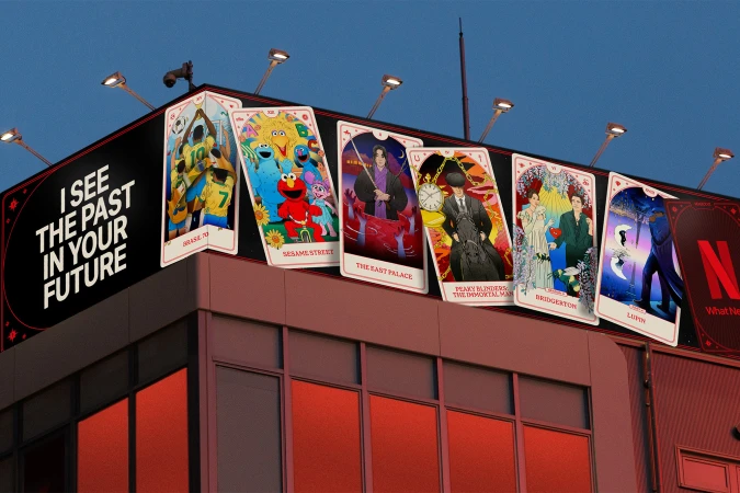 Rooftop billboard display featuring giant tarot-style illustrated cards depicting various Netflix shows against a dusk sky