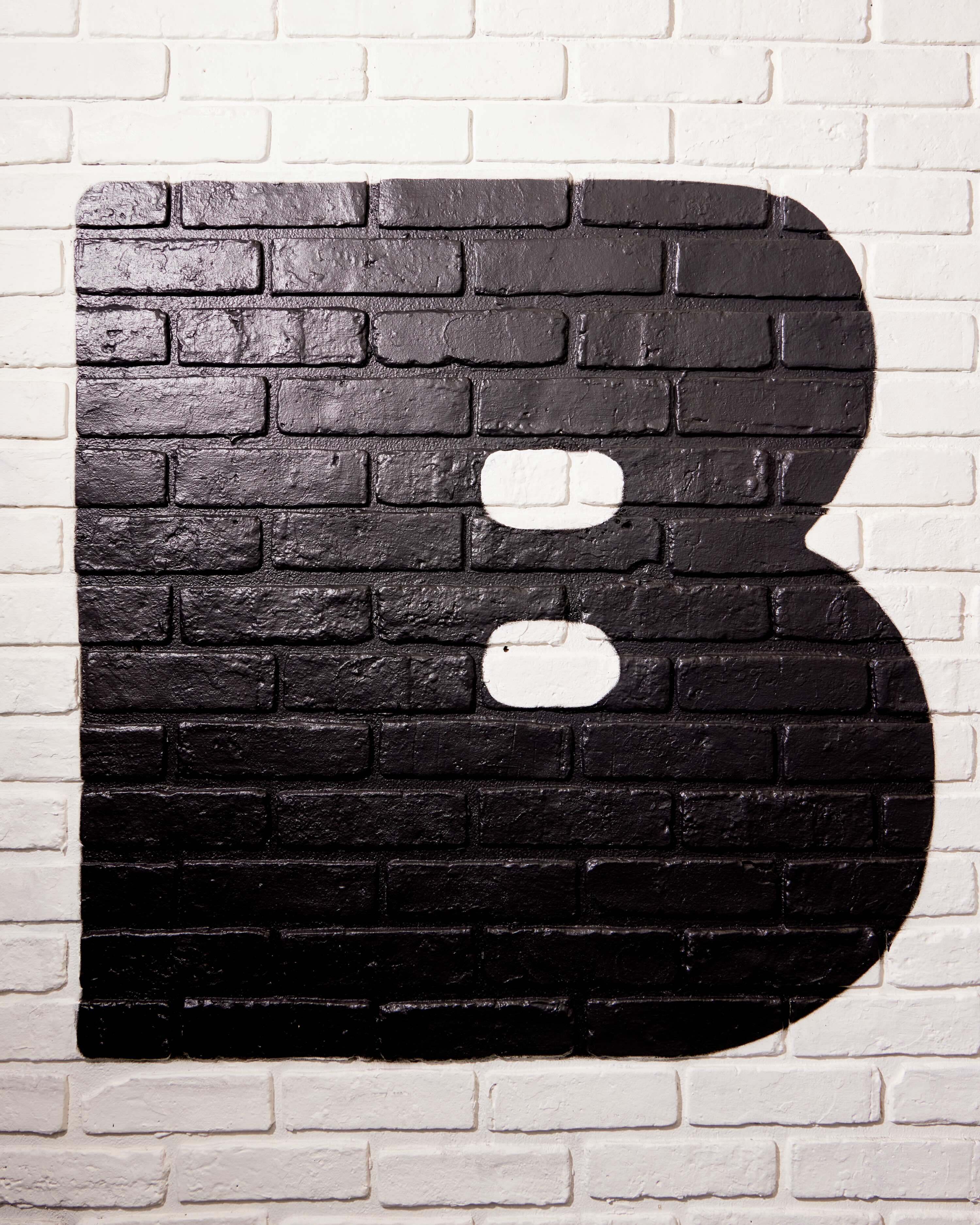 Black painted letter B on a white brick wall background for Bobbi's brand identity project.