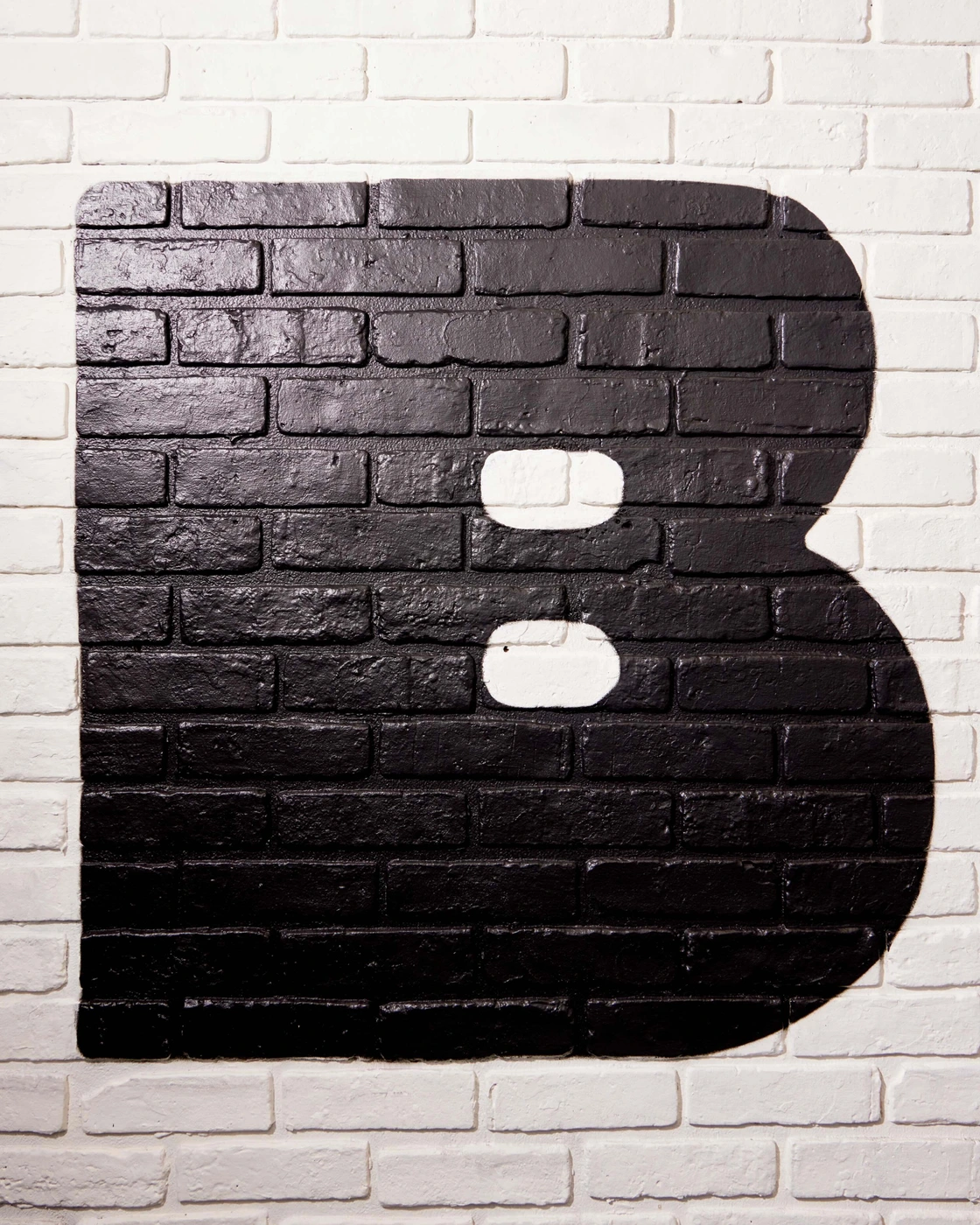 Black painted letter B on a white brick wall background for Bobbi's brand identity project.