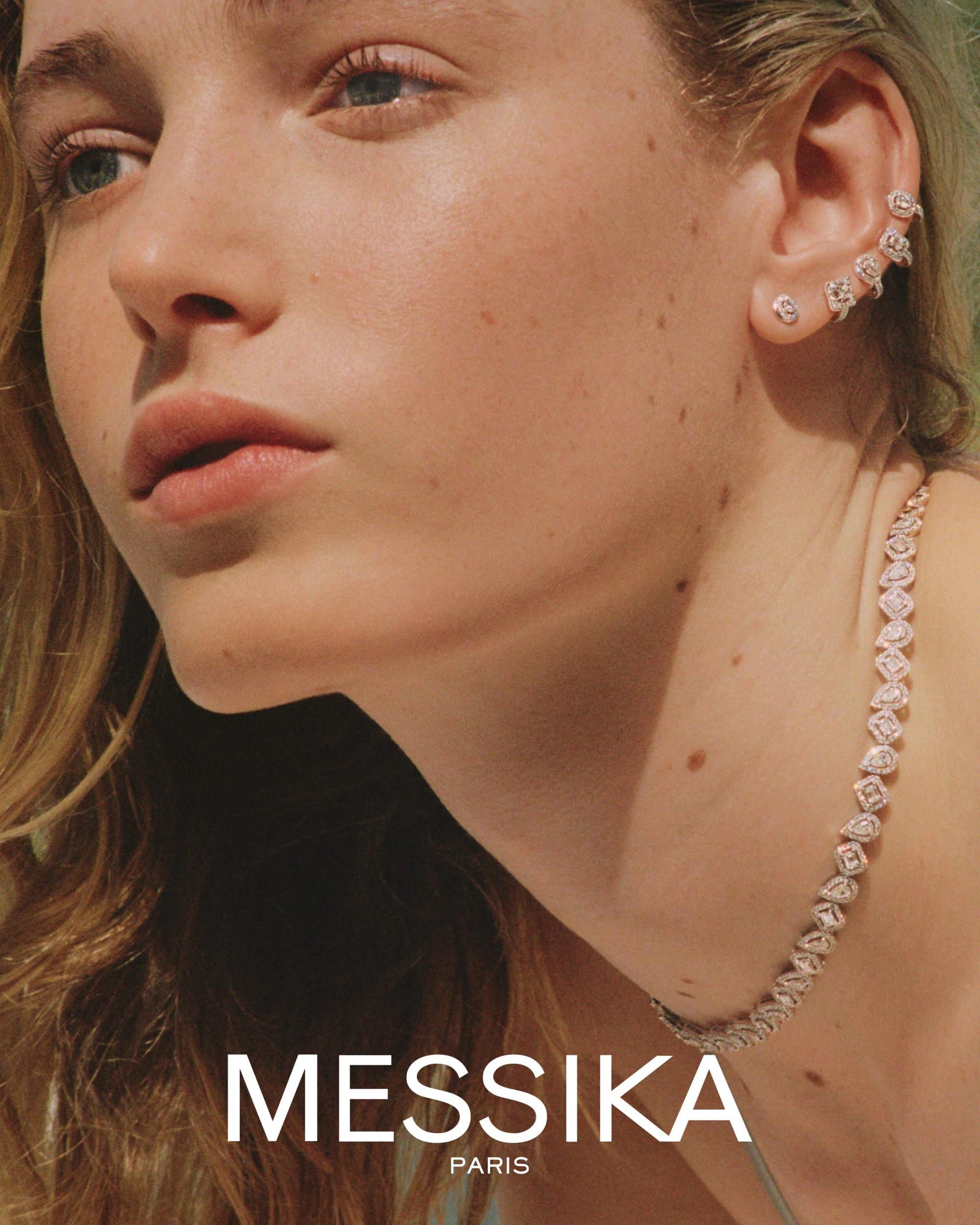 Close-up portrait of a woman wearing diamond earrings and a matching diamond necklace against an out-of-focus background.