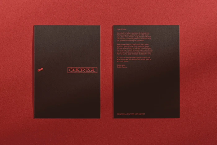Two dark stationery cards with red lettering placed flat on a textured dark red surface.