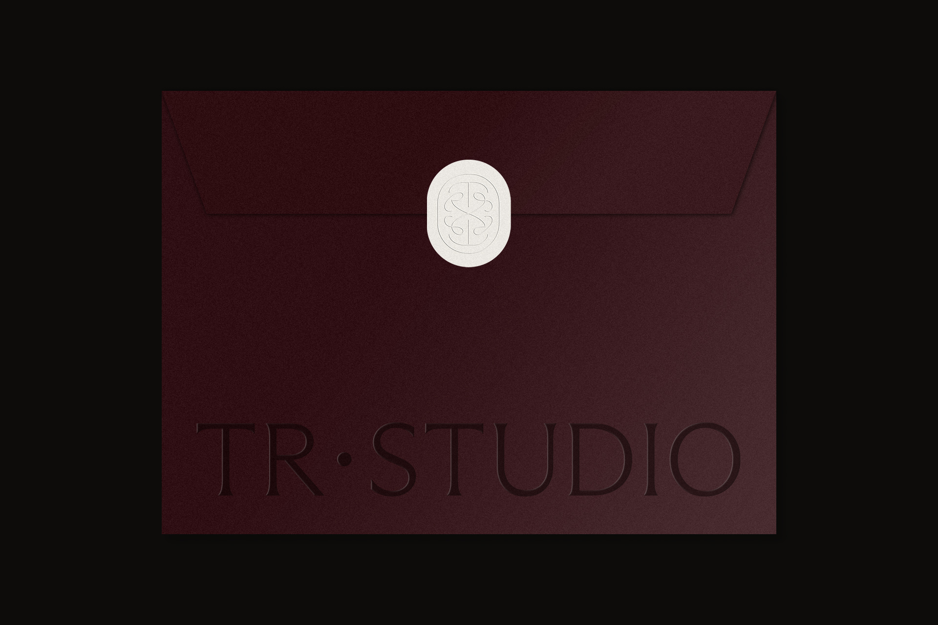 Deep burgundy envelope featuring an embossed white wax seal and embossed typography reading TR STUDIO against a black background.