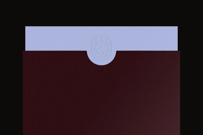 An embossed TR Studio logo on a light purple paper sleeve partially inserted into a dark burgundy folder against a black background.