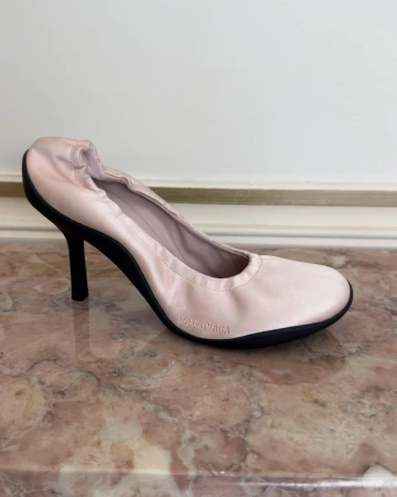 Balenciaga high-heeled shoe resting on a mottled marble surface against a plain white wall