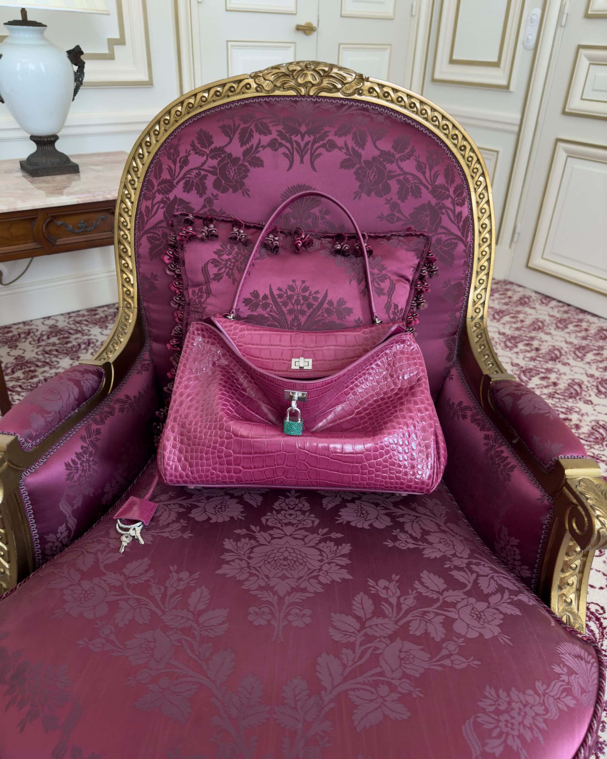 Pink exotic leather handbag resting on an ornate magenta damask armchair inside an elegant room
