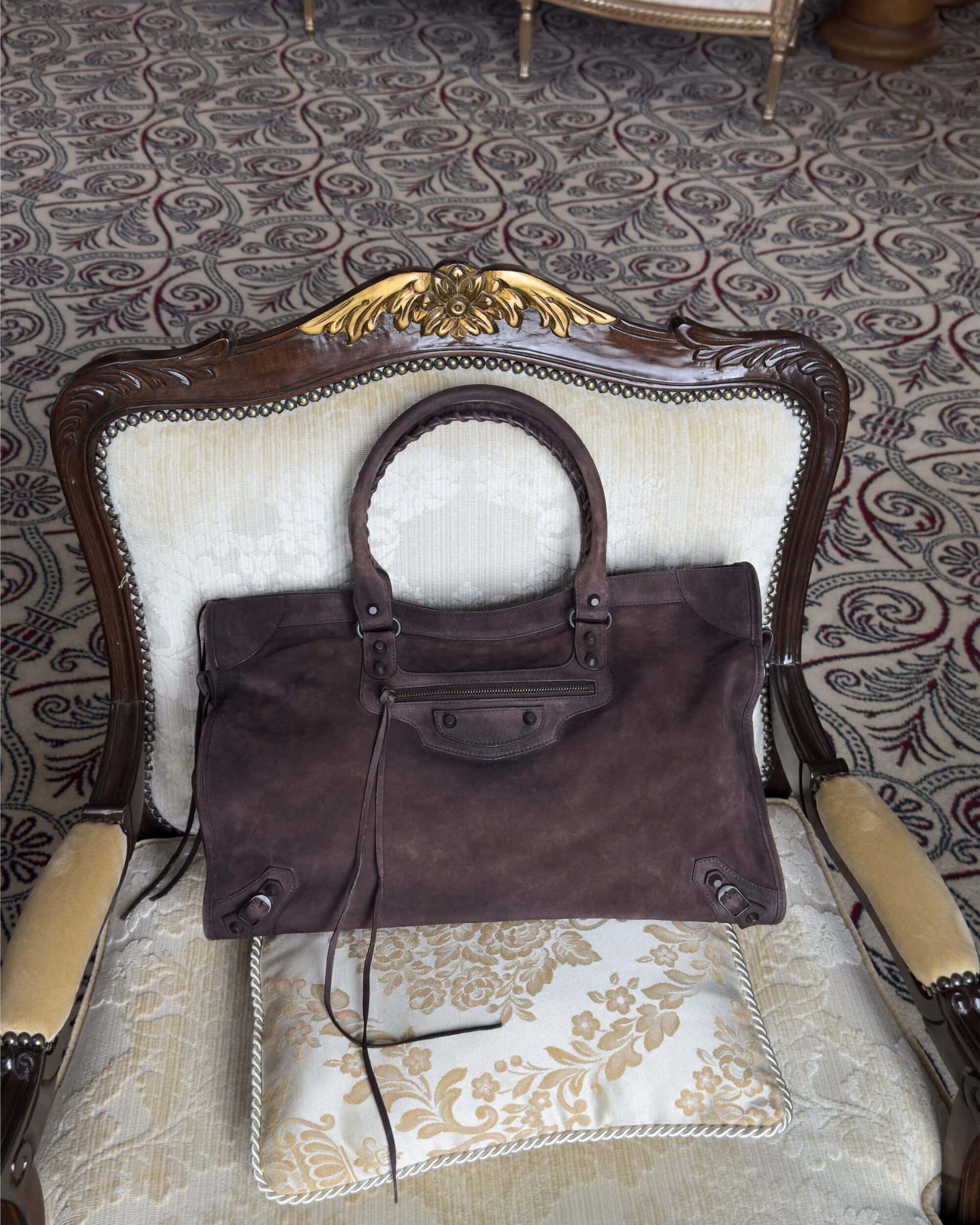 Brown leather handbag resting on an ornate armchair with patterned upholstery