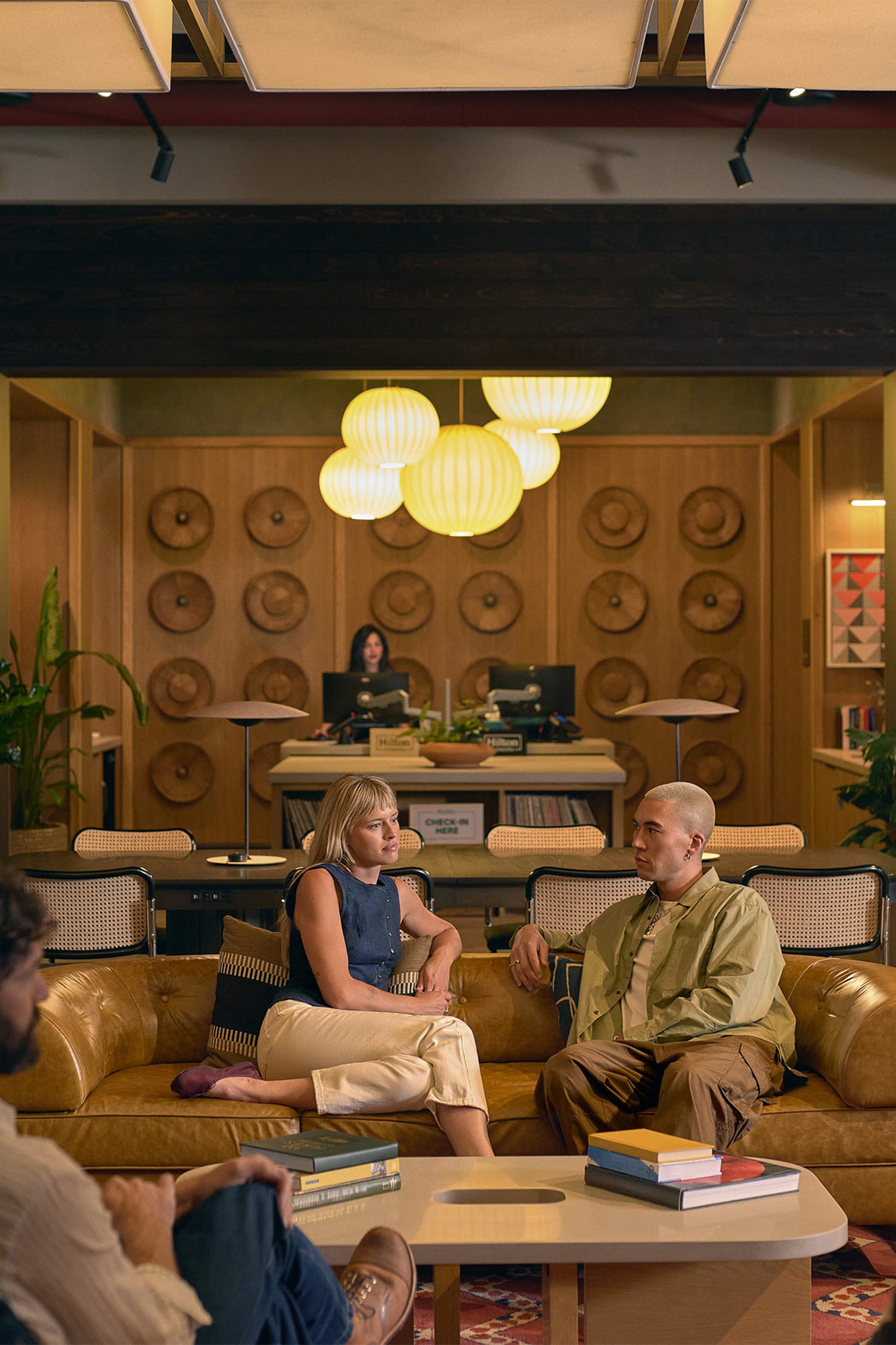 A man and woman seated on a yellow leather sofa in a hotel lobby interior