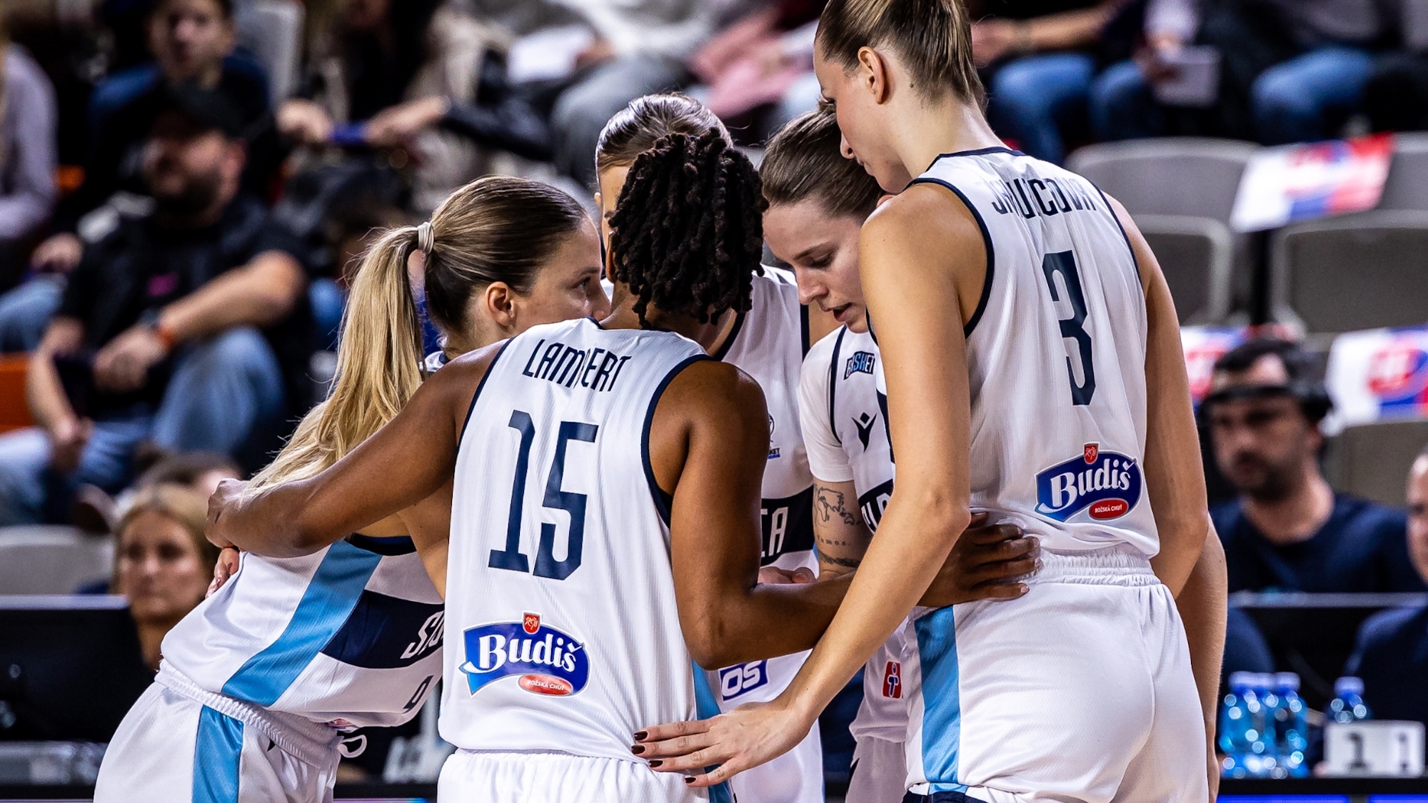 Basketball players in white and blue jerseys huddling together on court