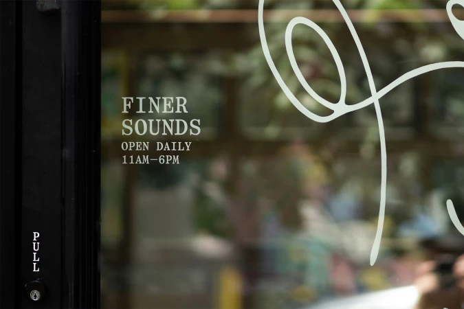Finer Sounds brand identity glass storefront window graphic with typography and open daily hours