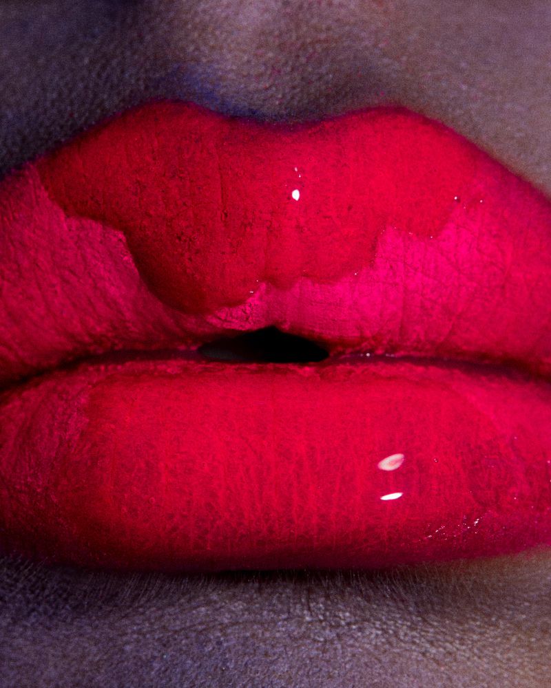 Extreme close-up of woman's red lips with a glossy texture, creating a bold and sensual beauty image emphasizing the vibrant color.
