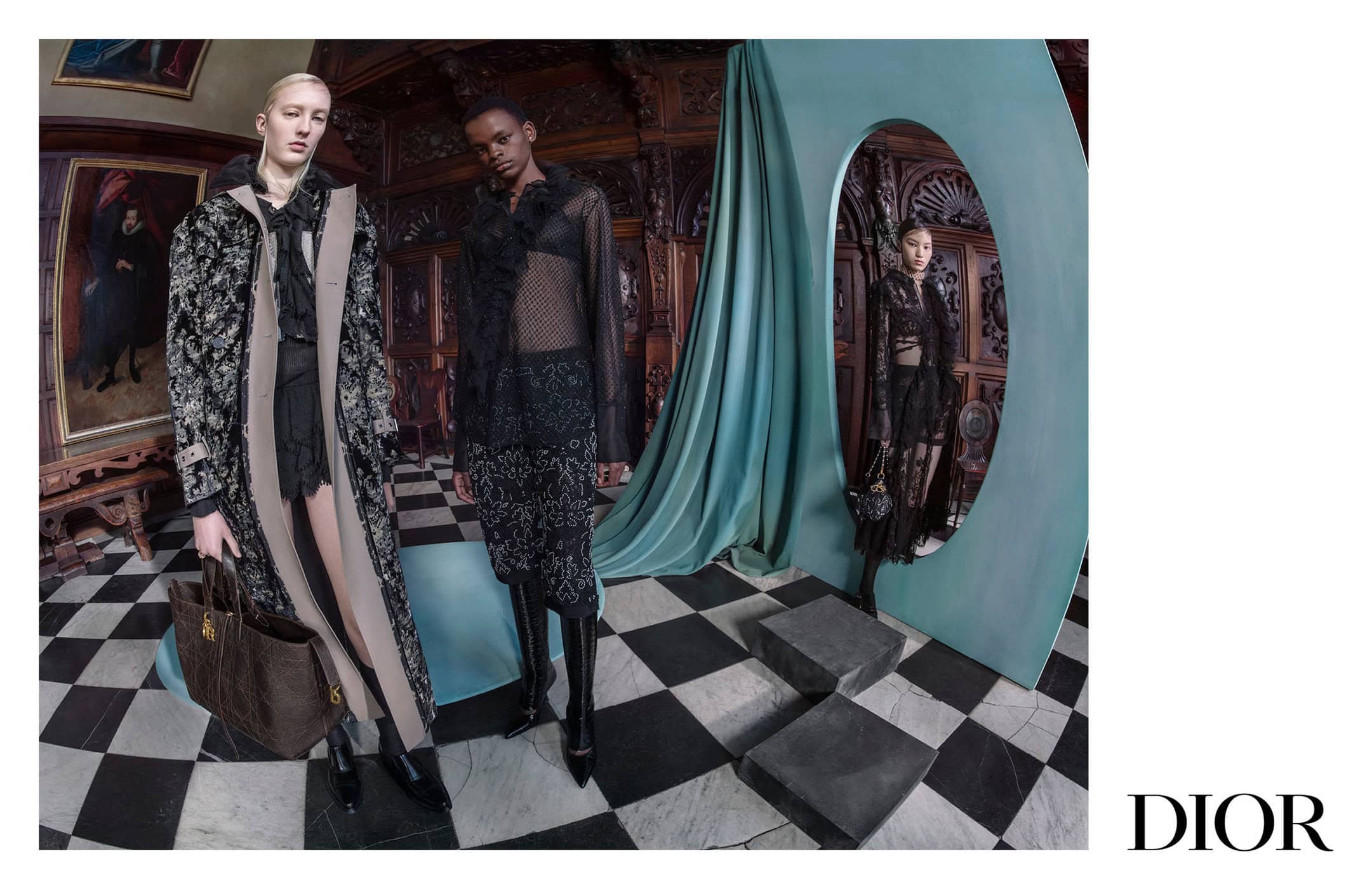 Three models in luxury dark fashion garments posing inside an opulent room with black and white checkered floor and a large teal archway.
