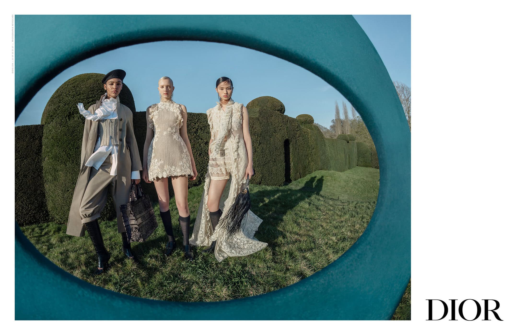 Three female models posing outdoors framed through a large teal circular opening, wearing Dior fashion collection clothing