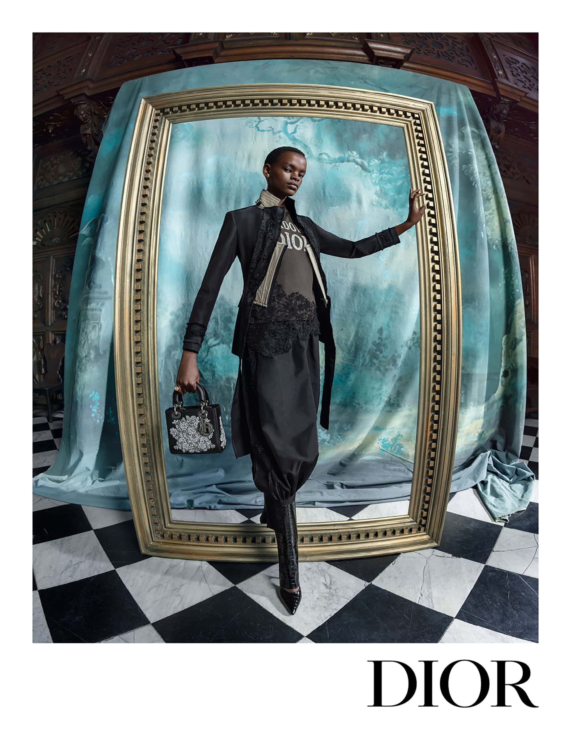 Model standing inside an ornate gold frame holding a patterned handbag in a Dior fall campaign image