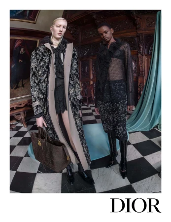 Two models in dark patterned Dior clothing standing on a black and white checkerboard floor in a wood-paneled room