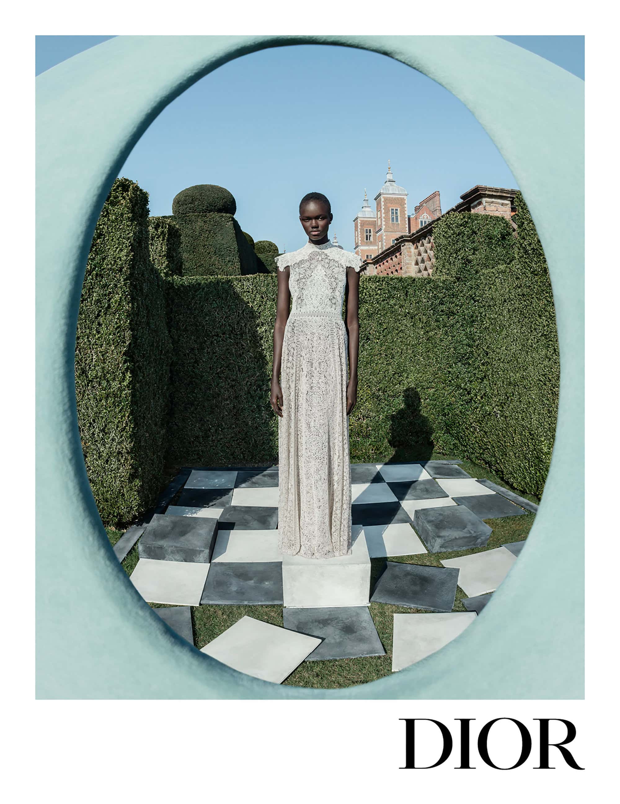 Model standing on a plinth within a topiary garden framed by a large arch, photographed for Dior Fall 2025 ad campaign.