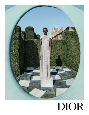 Model standing on a plinth within a topiary garden framed by a large arch, photographed for Dior Fall 2025 ad campaign.