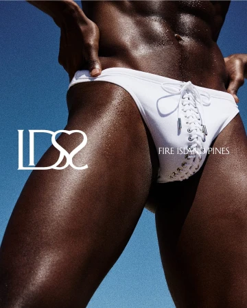 Close-up of a man wearing white lace-up swim briefs against a clear blue sky background.