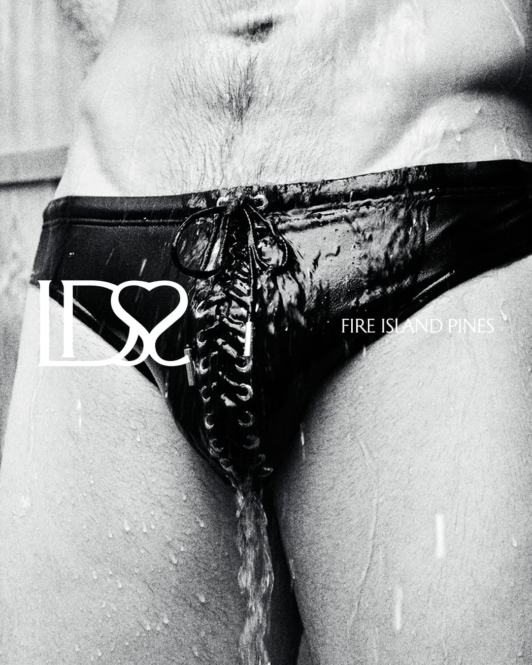 Close-up of a person wearing black lace-up swimwear with water droplets running down in a black and white campaign image.