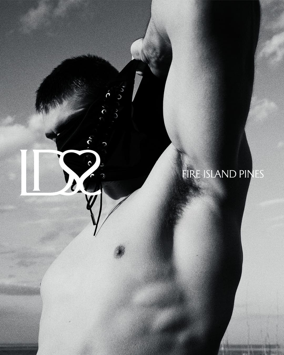 Monochrome close-up portrait of a shirtless man posing against an outdoor sky background for Ludovic de Saint Sernin.