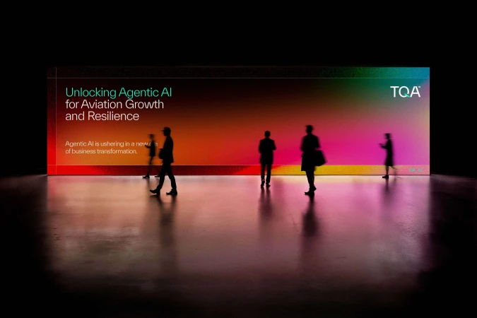 Silhouettes of five people walking past a large glowing screen displaying text and a vibrant gradient background