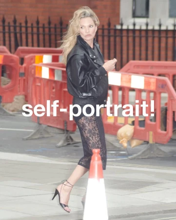 Kate Moss walking outdoors wearing a black leather jacket and lace skirt for Self-Portrait