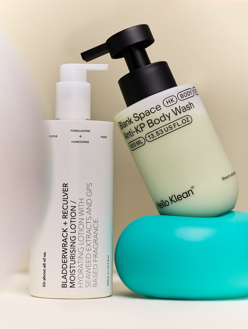 Two bottles of body wash and moisturising lotion from Hello Klean and Blank Space, displayed on a light background and blue podium.