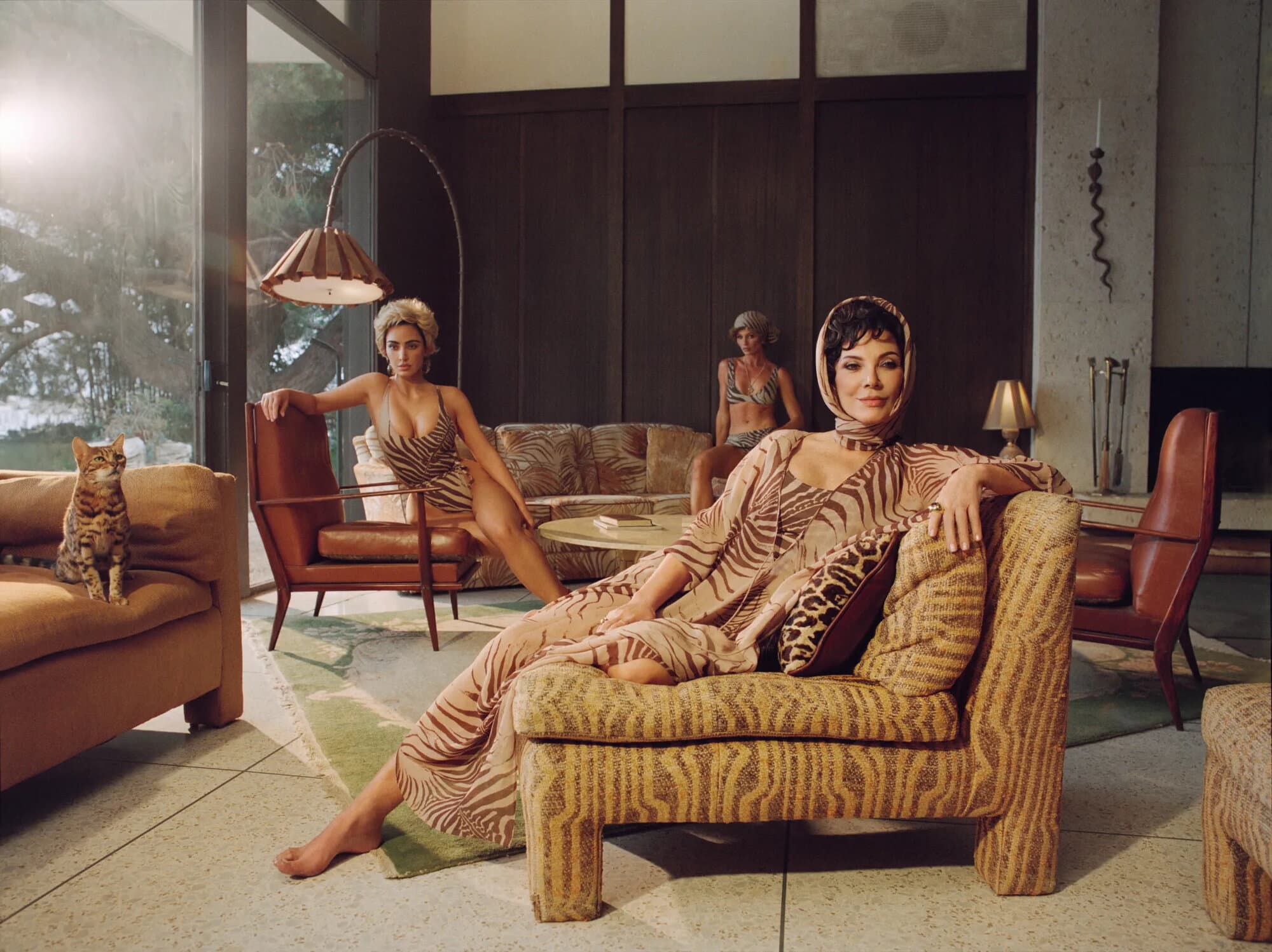 Kris Jenner and Kim Kardashian in animal print loungewear inside a midcentury modern living room with a cat.