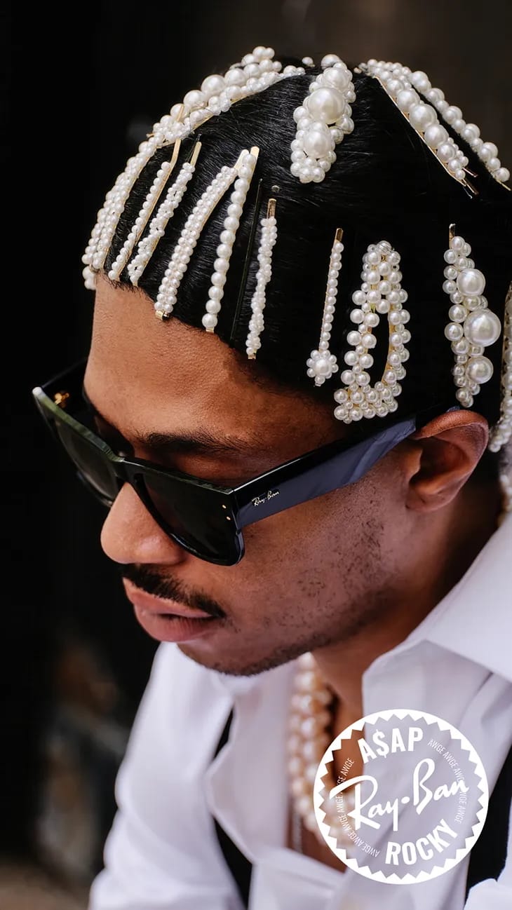 A$AP Rocky wearing black Ray-Ban sunglasses, a white shirt, and hair adorned with pearl hair clips for an ad campaign.