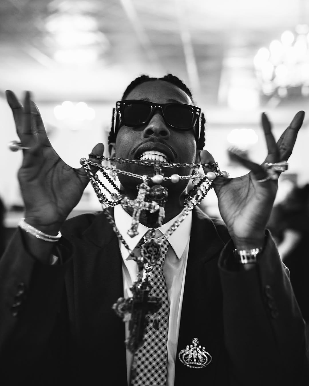 A$AP Rocky in a dark suit wearing sunglasses and holding multiple layered cross necklaces in the Ray-Ban advertising campaign.
