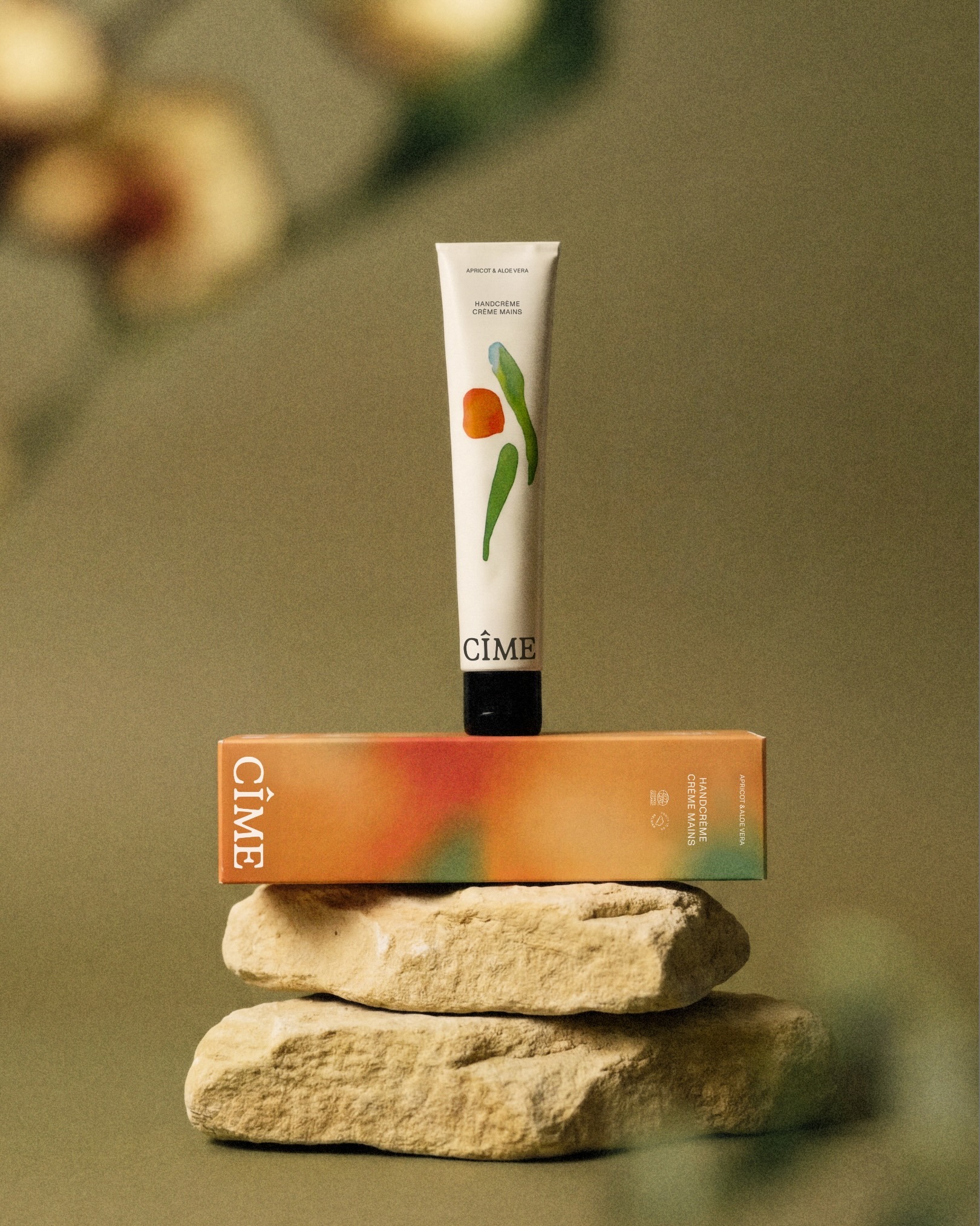 CIME skincare product tube standing upright on its packaging box, stacked on top of two natural stone blocks