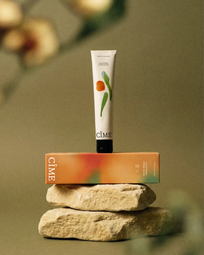 CIME skincare product tube standing upright on its packaging box, stacked on top of two natural stone blocks