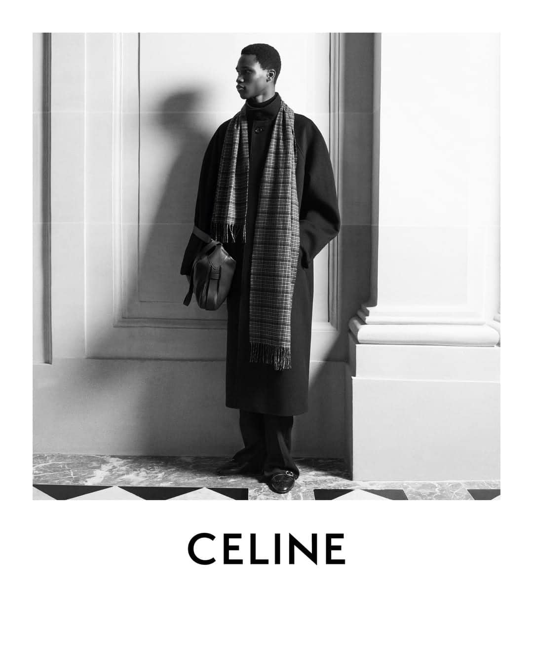 Monochrome fashion campaign image for Celine featuring a male model in a long dark coat and patterned scarf.