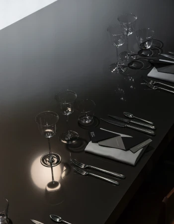 High angle shot of a sleek dark tabletop set with glassware, cutlery, folded napkins, and stationery for Matter and Shape.