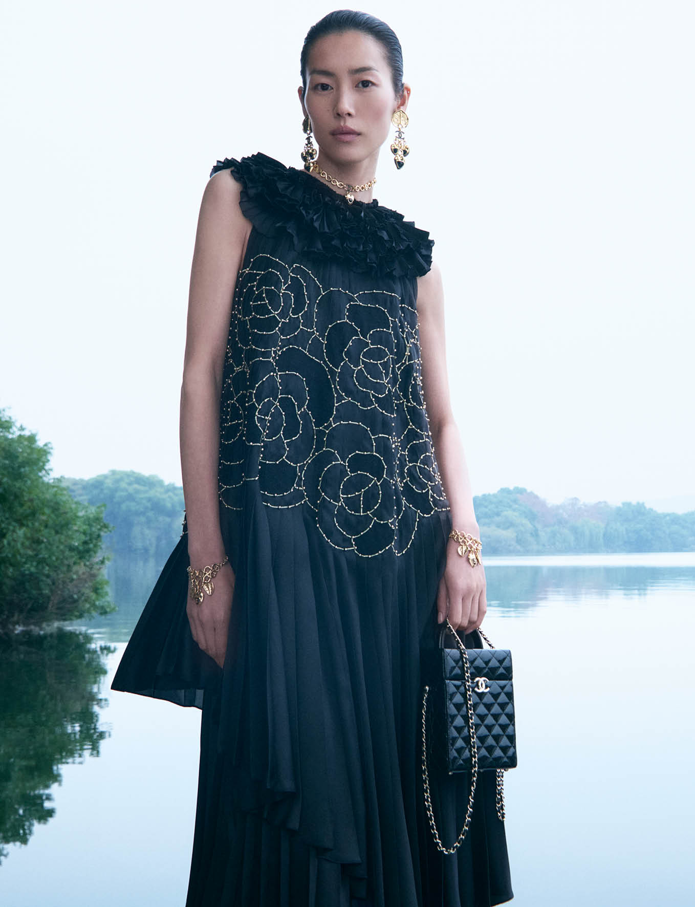 Model Liu Wen wearing a black embroidered dress by water for Chanel 2024/25 Metiers D'art ad campaign