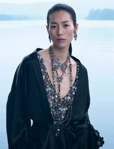 Model Liu Wen wearing a black silk robe and elaborate layered necklaces against an outdoor water background for Chanel