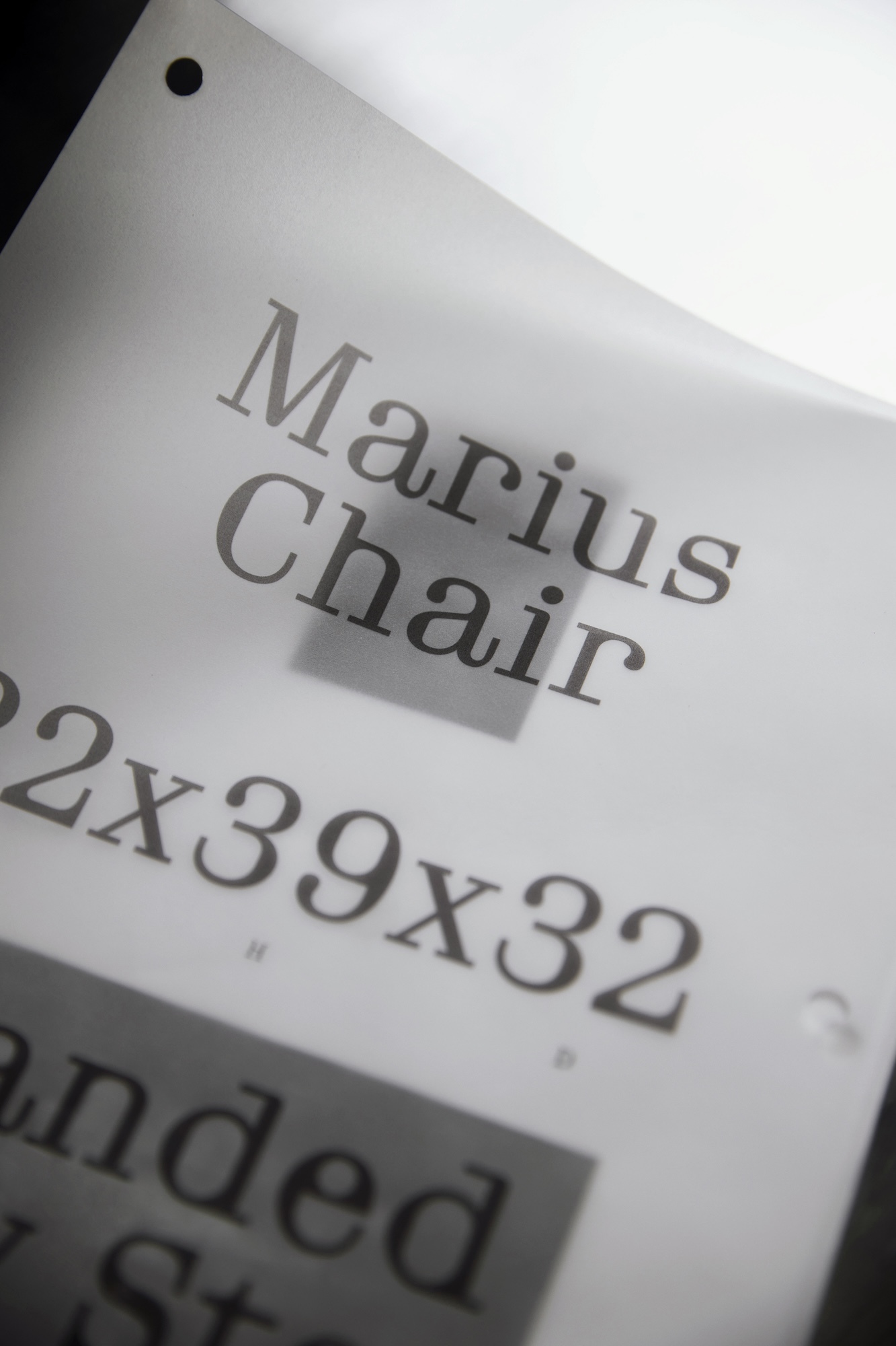 Printed product specification sheet for Marius Chair with text and dimensions against a bright backlight