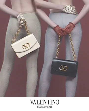 Two models standing from behind holding Valentino handbags behind their backs against a muted pink studio backdrop.