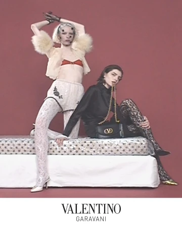 Two models posing on a mattress with a black Valentino handbag in an ad campaign by Sharna Osborne.