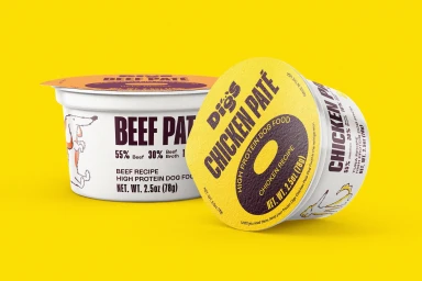 Two Digs dog food packaging cups with chicken pate and beef pate labels set against a solid yellow background.