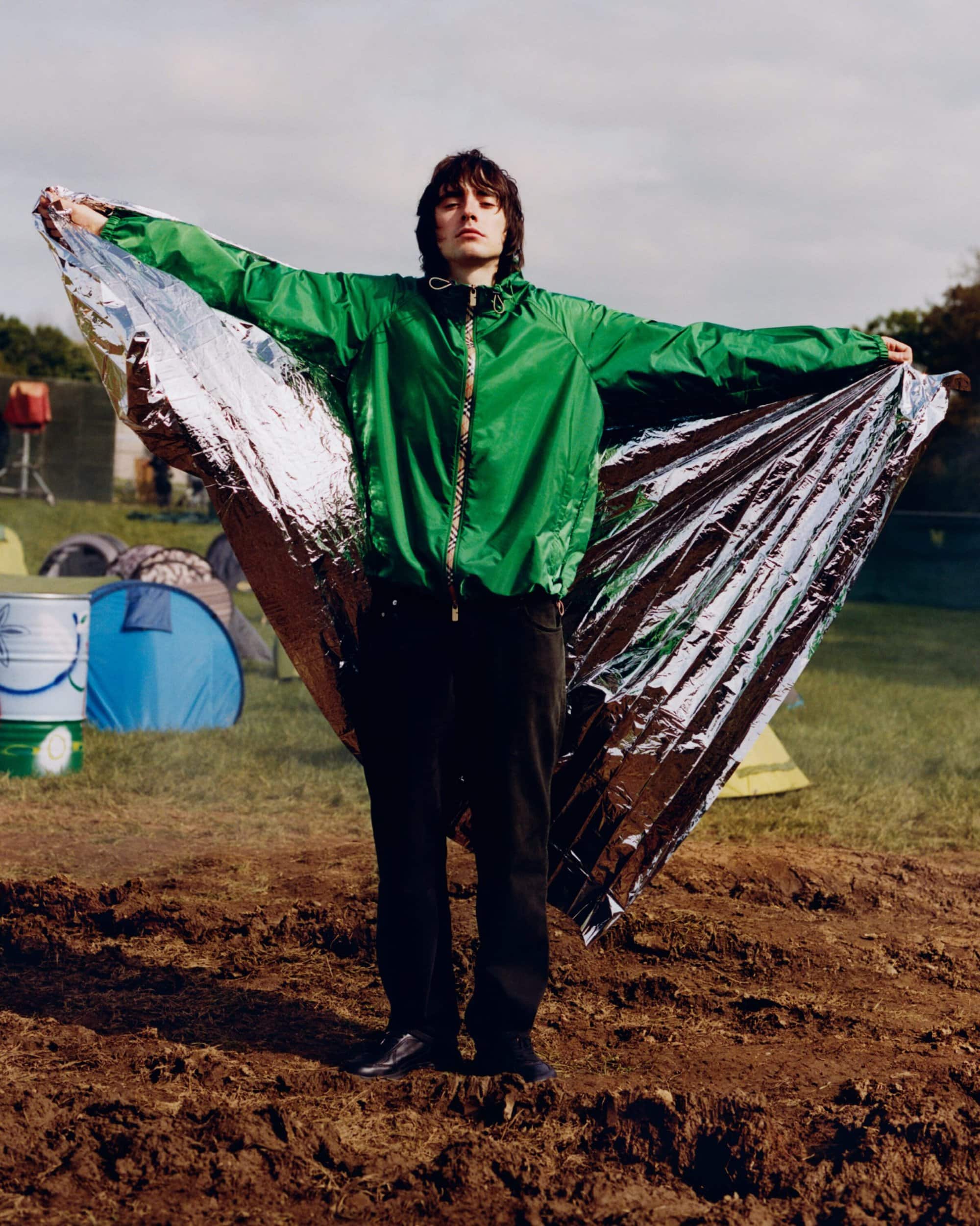 Person wearing a bright green jacket holding out a reflective emergency blanket like wings outdoors