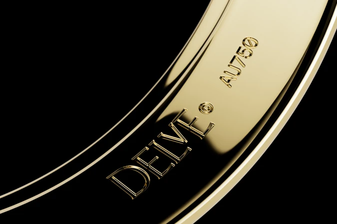 Macro close-up shot of engraved gold ring showing DEIVE and AU750 hallmark against a dark background