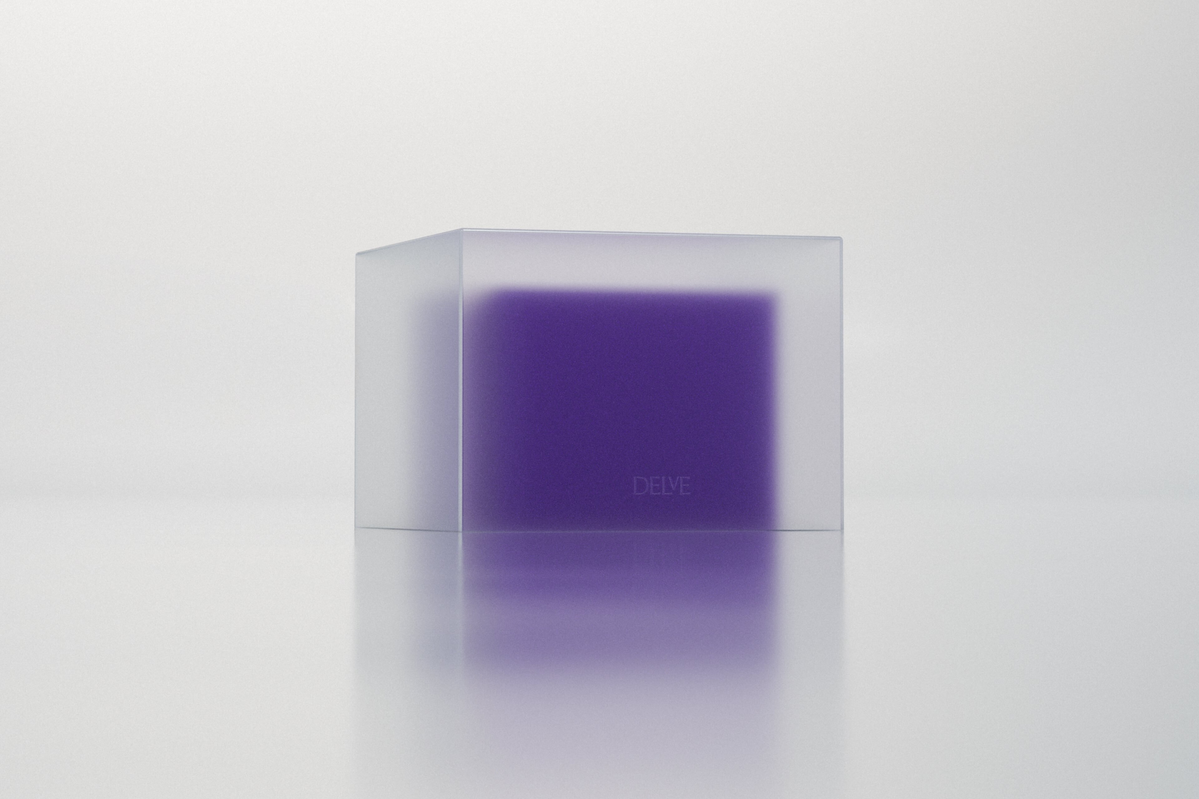A purple rectangular block inside a translucent frosted glass cube on a white surface with a soft reflection below