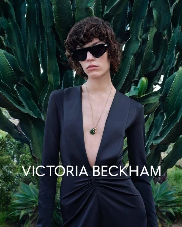 Model Alix Bouthors wearing black sunglasses and a black dress in front of tall cactus plants for Victoria Beckham