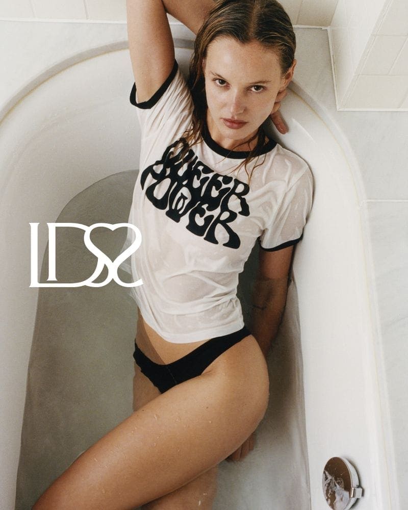 Model wearing a wet white ringer t-shirt and black briefs inside a porcelain bathtub for Ludovic de Saint Sernin